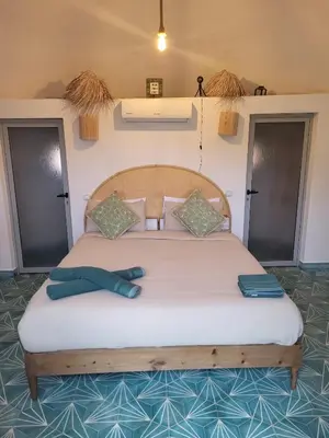 a bedroom with a large bed with two blue shoes on it at Les Domes de l Ourika in Sidi Bouzguia