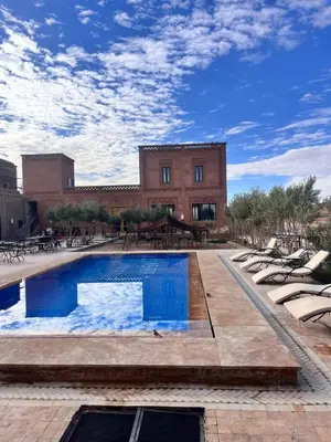 a swimming pool with lounge chairs in front of a building at Itrane sahara Auberge in Taouz