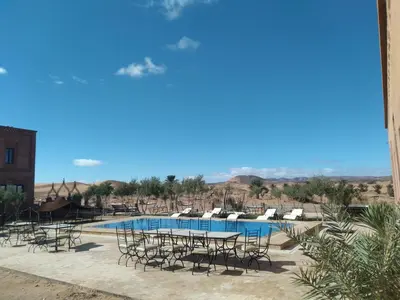 a view of a pool with chairs and a table at Itrane sahara Auberge in Taouz