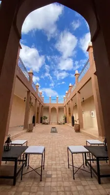 an empty courtyard with benches in a building at Itrane sahara Auberge in Taouz