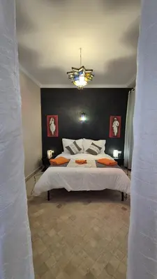a bedroom with a large bed and a chandelier at Itrane sahara Auberge in Taouz