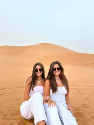 two women sitting in the sand in the desert at Star Desert Camp Merzouga in Merzouga