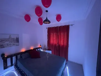 a bedroom with a bed with red curtains and balloons at Luxury Jacuzzi Apartment with Romantic Decoration in Fès