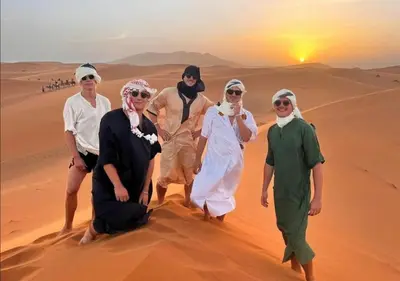 a group of people walking in the desert at Top Desert Camp in Merzouga