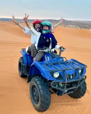 two people riding on a wheeler in the desert at Top Desert Camp in Merzouga