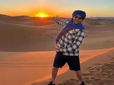 a man standing in the desert at sunset at Top Desert Camp in Merzouga