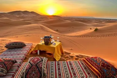 a table in the desert with the sunset in the background at Top Desert Camp in Merzouga