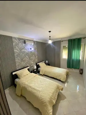two beds in a bedroom with green curtains at appartement luxe in Meknès