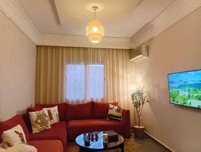 a living room with a red couch and a tv at Appartement moderne 2 chambres À 5 min de l'aéroport RAK avec Wi-Fi rapide in Oulad Akkou