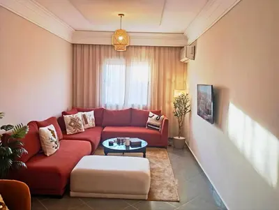 a living room with a red couch and a table at Appartement moderne 2 chambres À 5 min de l'aéroport RAK avec Wi-Fi rapide in Oulad Akkou