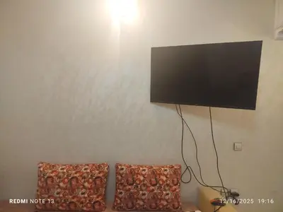 a flat screen tv hanging on a wall with two pillows at Otmania house Meknès in Meknès
