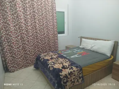 a small bedroom with a bed and a curtain at Otmania house Meknès in Meknès