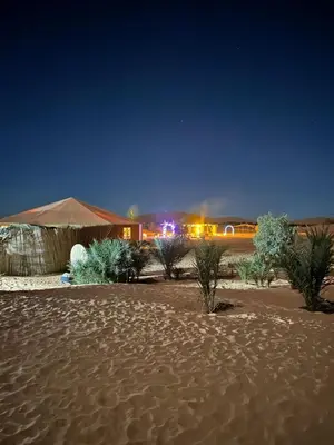 a desert with a tent and trees in the sand at Désert camp berbère Sahara in Merzouga