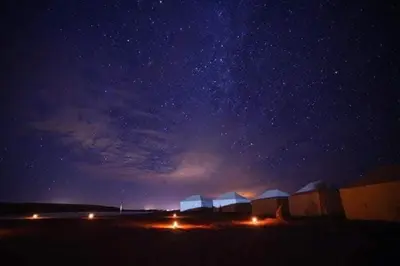 a night view of a starry sky with buildings and lights at Désert camp berbère Sahara in Merzouga