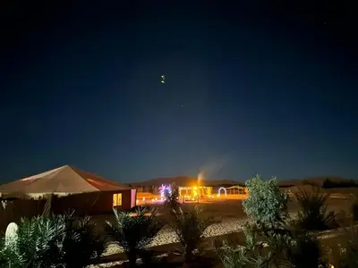 a building with a tent and lights in the night at Désert camp berbère Sahara in Merzouga