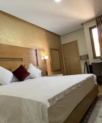 a bedroom with a large white bed in a room at Hôtel Vallée Ziz in Er Rachidia