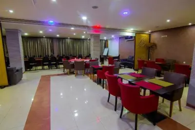 a dining room with tables and red chairs at Hôtel Vallée Ziz in Er Rachidia