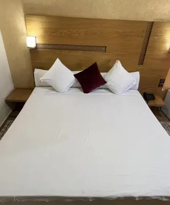 a large white bed with three pillows on it at Hôtel Vallée Ziz in Er Rachidia