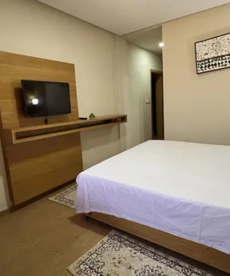 a bedroom with a bed and a flat screen tv at Hôtel Vallée Ziz in Er Rachidia