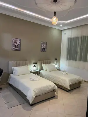 two beds in a bedroom with a chandelier at Spacious Family Apartment in Er Rachidia