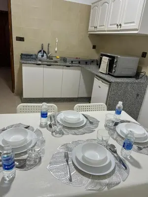 a white table with plates and glasses on it at Spacious Family Apartment in Er Rachidia