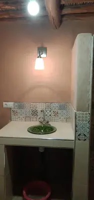 a bathroom with a sink with a light above it at Jnan Ksar el Kdim - Studios Safran, Jasmin et Cannelle in Mhamid