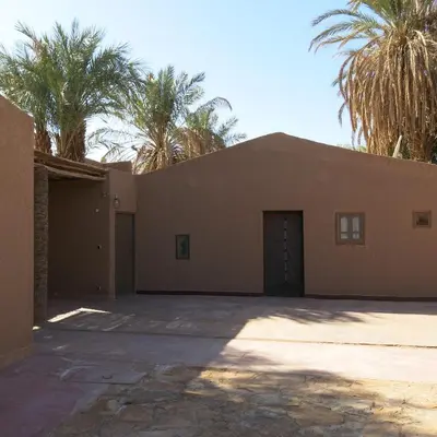 a building with palm trees in front of it at Jnan Ksar el Kdim - Studios Safran, Jasmin et Cannelle in Mhamid