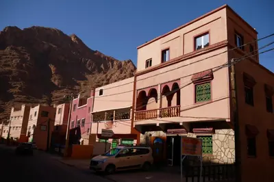 a white car parked in front of a building with a mountain at La Belle étoile in Aït Oussane