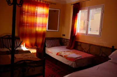 a small bedroom with two beds and a window at La Belle étoile in Aït Oussane