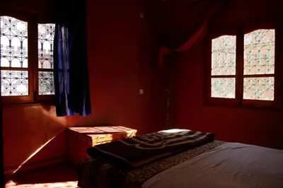 a bedroom with two windows and a bed in it at La Belle étoile in Aït Oussane