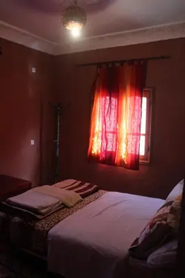 a bedroom with a bed and a window with red curtains at La Belle étoile in Aït Oussane
