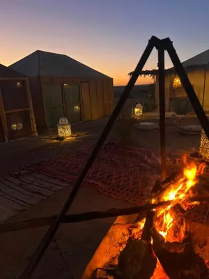a fire pit in front of a building at sunset at Fabulous Royal Camp in Merzouga