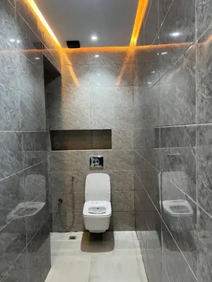 a bathroom with a toilet and a tiled wall at Haut standing apartment in hearth of fez in Fès