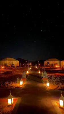 a long road with candles and lights in the night at Desert Halo Camp in Merzouga