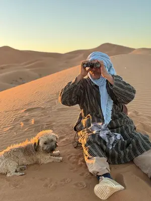 a man in the desert taking a picture with a dog at Desert Halo Camp in Merzouga