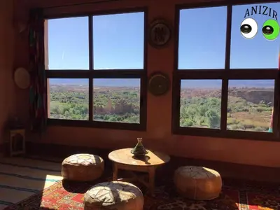 a room with large windows and a table and stools at Kasbah Anizir Itran in Kalaat MGouna