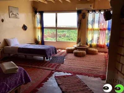 a bedroom with a bed and a large window at Kasbah Anizir Itran in Kalaat MGouna