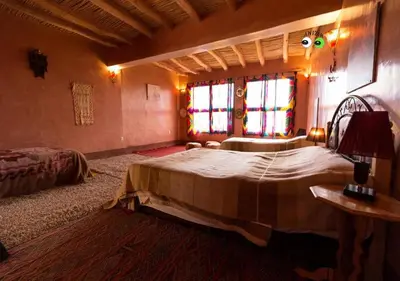 a bedroom with two beds and two windows at Kasbah Anizir Itran in Kalaat MGouna