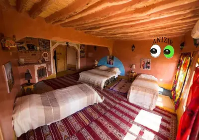 a bedroom with two beds with eyes on the wall at Kasbah Anizir Itran in Kalaat MGouna