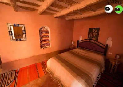 a bedroom with a bed and a window with eyeballs at Kasbah Anizir Itran in Kalaat MGouna