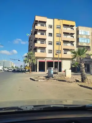 a building on the side of a street with palm trees at mina residence