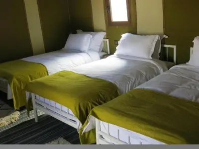 a room with two beds with green and white sheets at merzouga best luxury camp in Merzouga