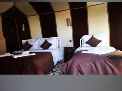 a bedroom with two beds with white sheets and pillows at merzouga best luxury camp in Merzouga