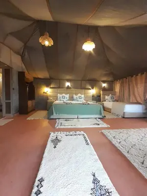 a room with a bed and several rugs on the floor at merzouga best luxury camp in Merzouga
