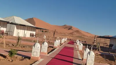 a red carpet path in the middle of the desert at merzouga best luxury camp in Merzouga