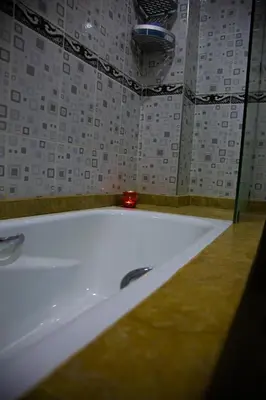 a white bath tub in a bathroom with a tile wall at Nise Apartment in Oulad Akkou