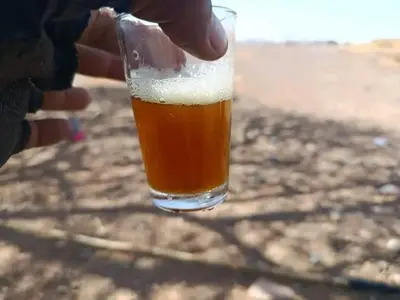 a person is holding a glass of beer at M'hamid El Ghizlane, Provinz Zagora in Oulad Akkou
