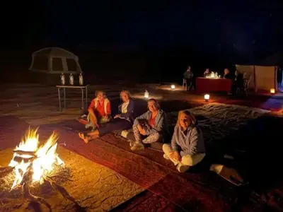a group of people sitting around a fire at M'hamid El Ghizlane, Provinz Zagora in Oulad Akkou
