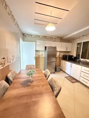 a kitchen with a long wooden table and chairs at modern family stay in Meknès