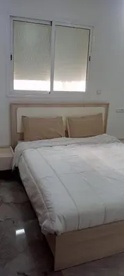 a bed in a room with two windows at Appartement Fès standing in Fès